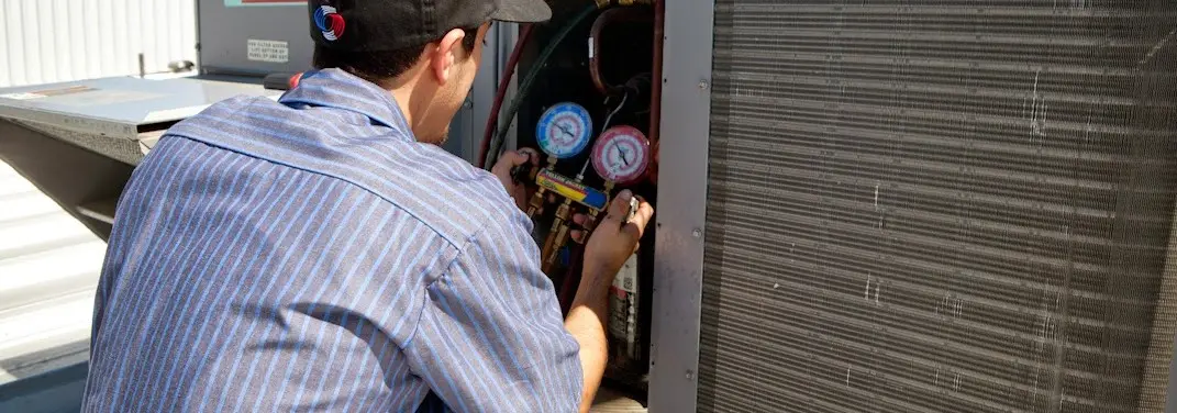 HVAC technician servicing a condenser unit in Pensacola Station