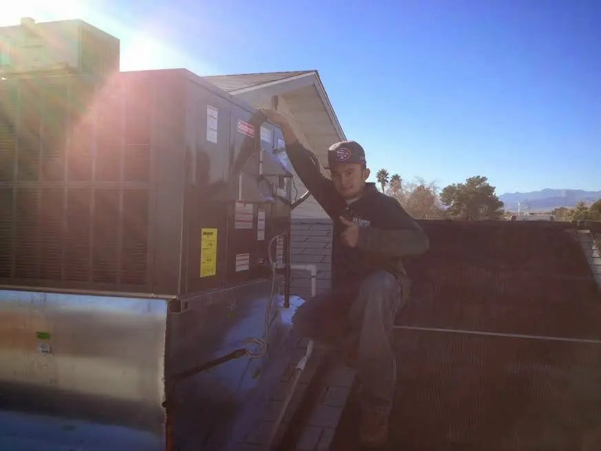HVAC technician performing AC Tune-Up on a rooftop unit in Pensacola Station